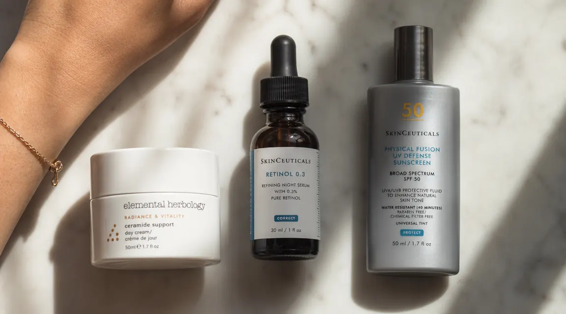 Skincare flatlay showing retinol serum, a ceramide moisturizer, and SPF on a marble surface